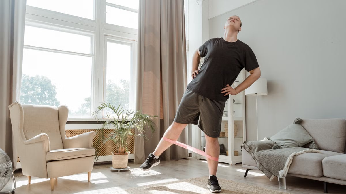 Man performs exercise in living room with resistance band, promoting home fitness.